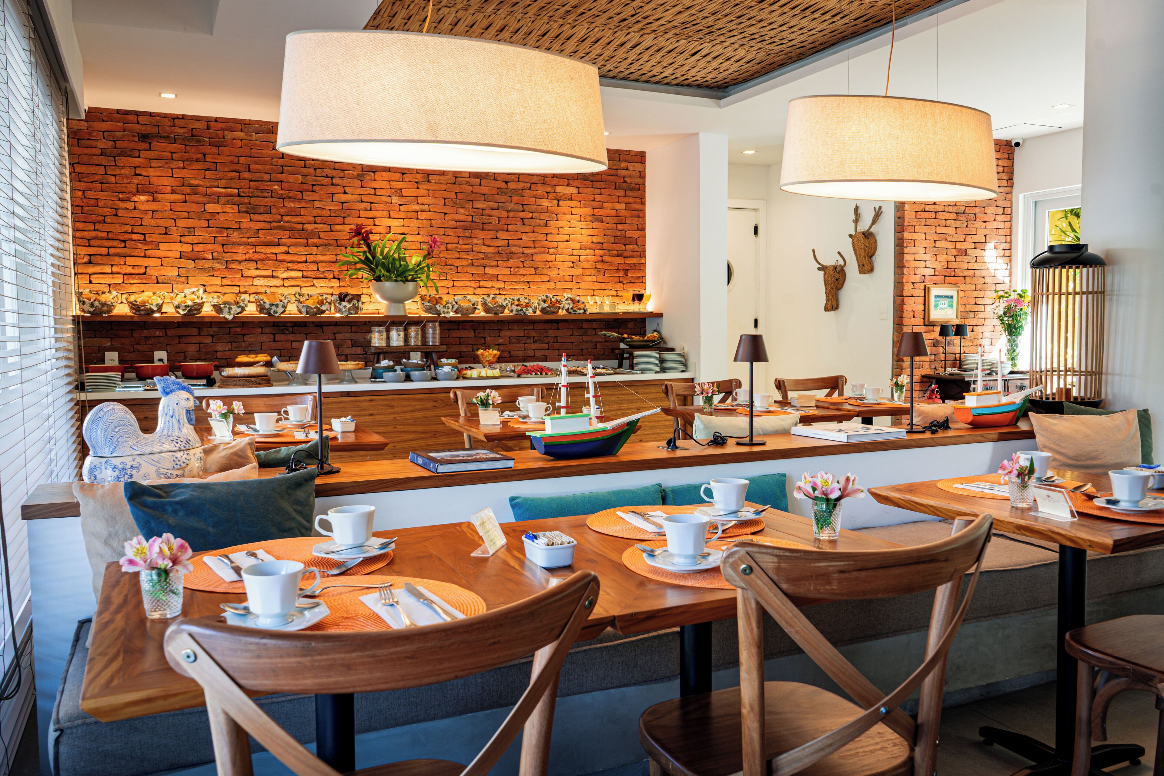 Un restaurant avec des tables et des chaises en bois, un mur en briques et des lampes suspendues.