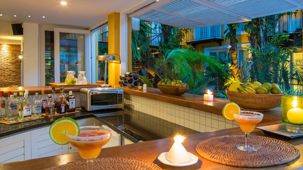 Un área de bar con temática tropical, que incluye una variedad de botellas y una vela sobre la barra.