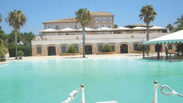 A large swimming pool with a building in the background. - iH Hotels Agrigento Kaos Resort (Agrigento)