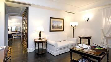 Un salon moderne avec un canapé blanc, une table basse sur laquelle sont posés des magazines, un tableau encadré au mur et une table d’appoint avec une lampe.