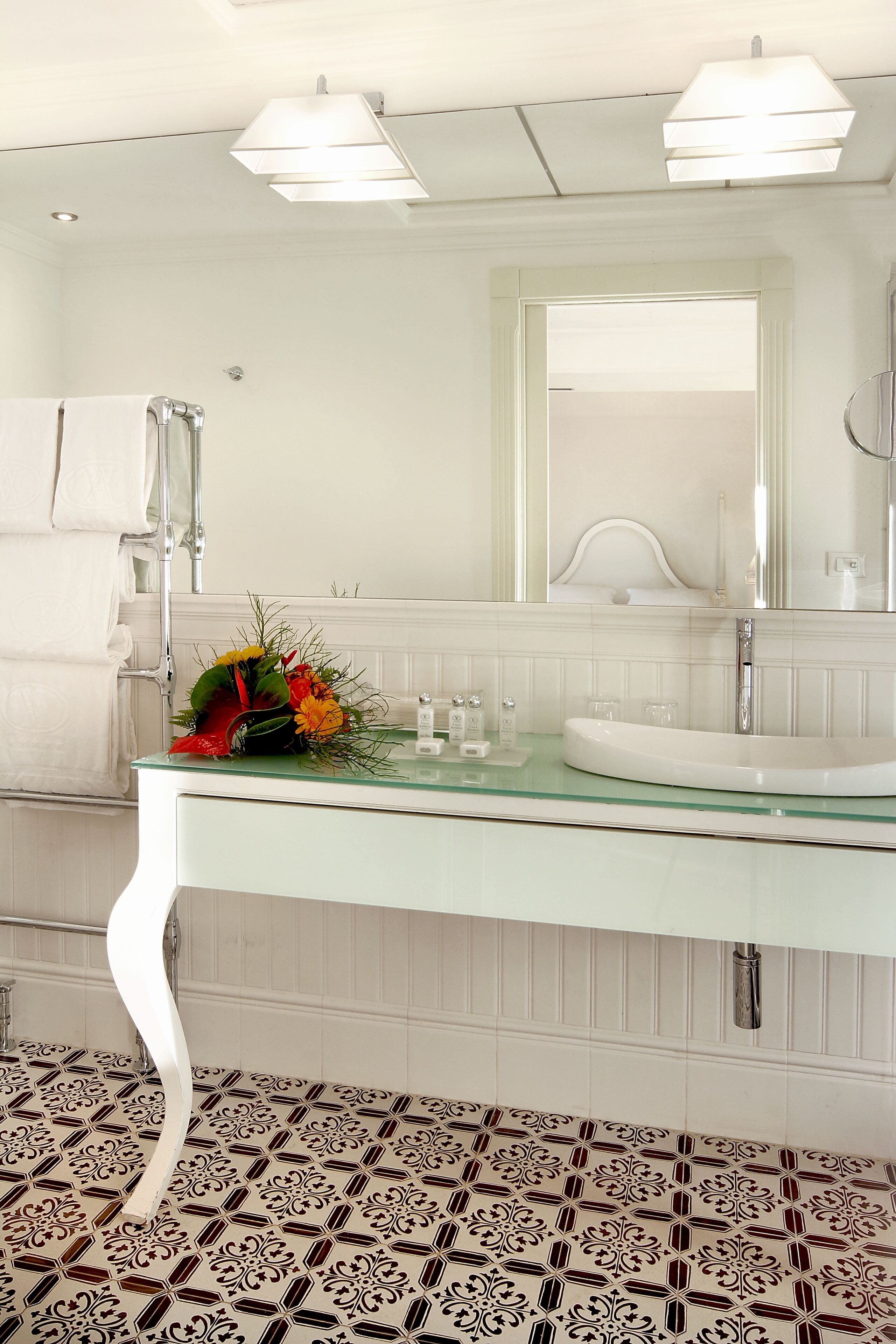 Une salle de bain moderne avec un lavabo en verre, un meuble-lavabo blanc et des carreaux de sol à motifs.