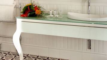 Une salle de bain moderne avec un lavabo en verre, un meuble-lavabo blanc et des carreaux de sol à motifs.