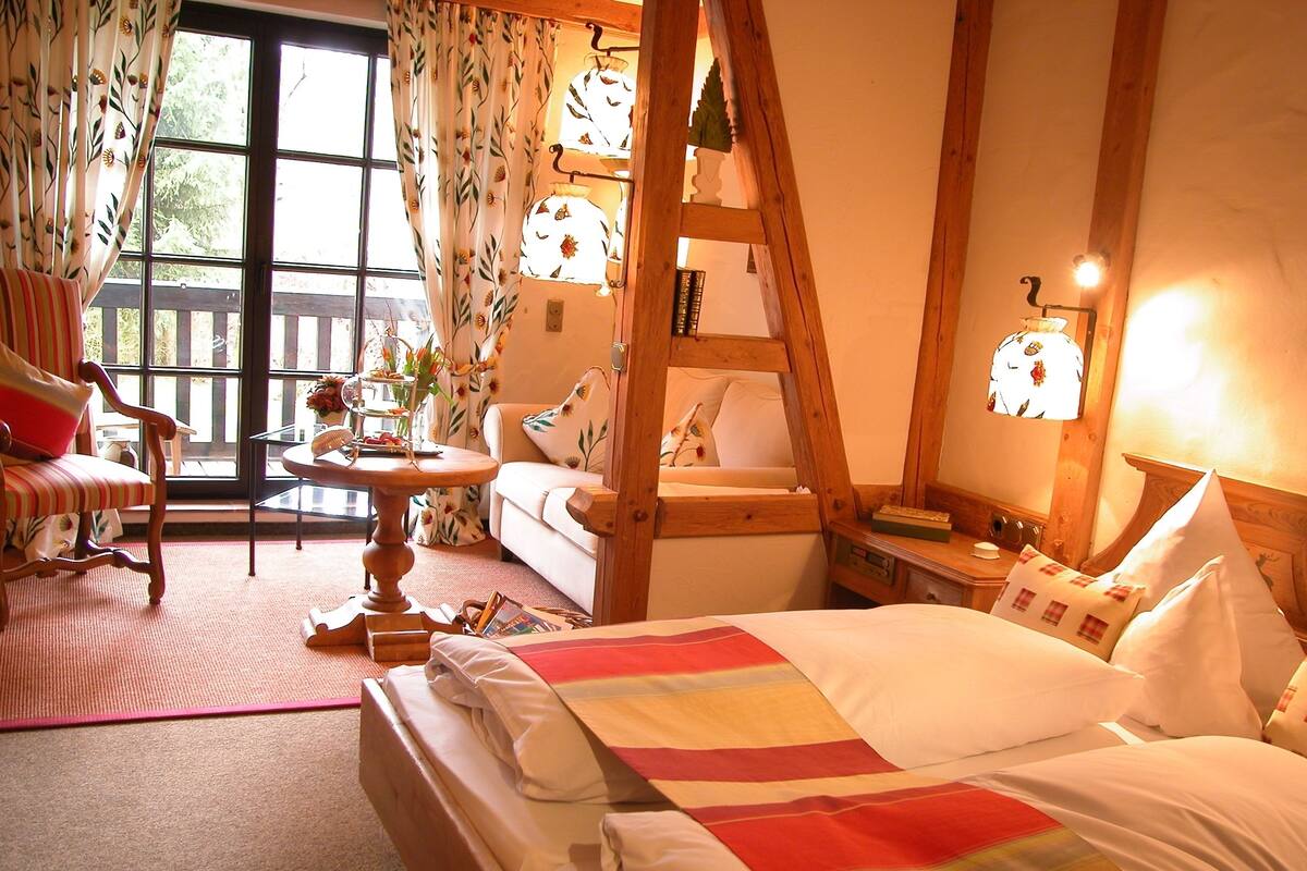 Een gezellige kamer met een bed, een stoel, een tafel en een raam met gordijnen.