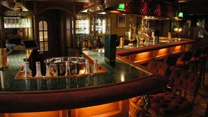 A bar area with a curved counter, bar stools, and a variety of bottles and glasses. - Hotel Jagdhof Glashütte (Bad Laasphe)