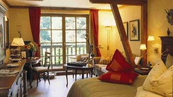 Ein gemütliches Schlafzimmer mit Bett, Schreibtisch und Stuhl. Ein Fenster mit Vorhängen bietet Blick auf die grüne Umgebung.