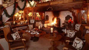 A warmly lit room with a fireplace, Christmas decorations, and a deer head mounted on the wall. - Hotel Jagdhof Glashütte (Bad Laasphe)