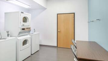 A laundry room with a wooden door, a table, and two washing machines.
