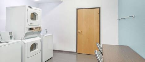 A laundry room with a wooden door, a table, and two washing machines.