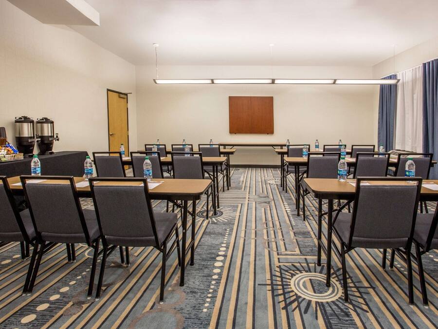 A conference room with a long table, rows of chairs, and a carpeted floor.