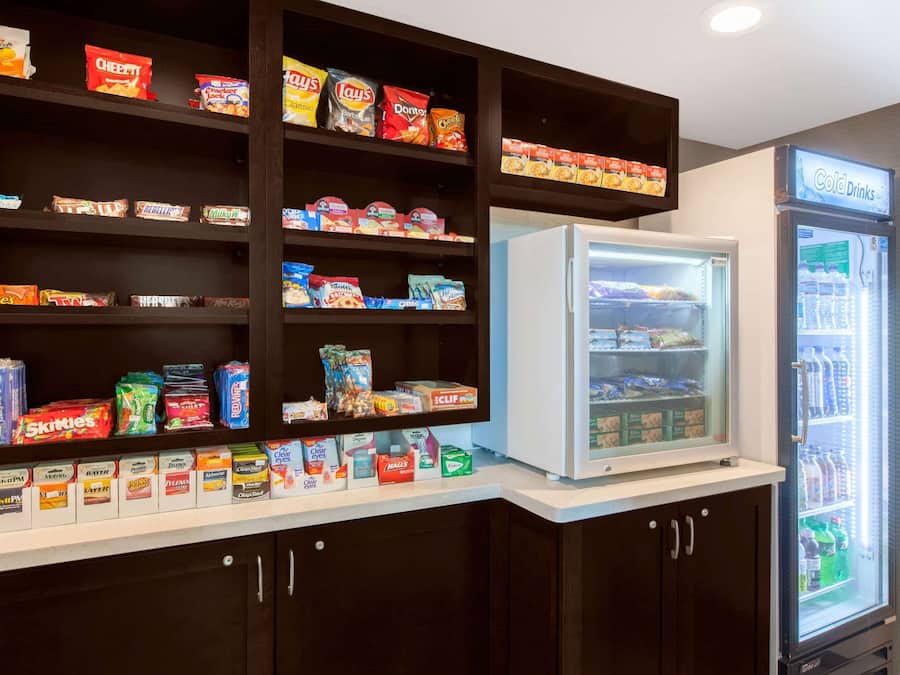 A snack and beverage vending area with various snack options and a refrigerator.