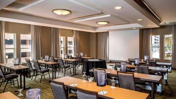 A conference room with tables, chairs, and a projector screen.