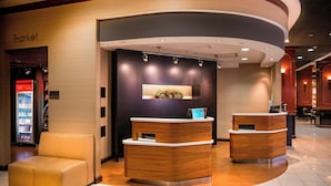 Un espace d’accueil comprenant un comptoir de réception en bois, un coin salon et un réfrigérateur.