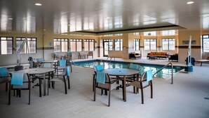 Un espace piscine intérieure doté de plusieurs coins salon et d’une table de billard.