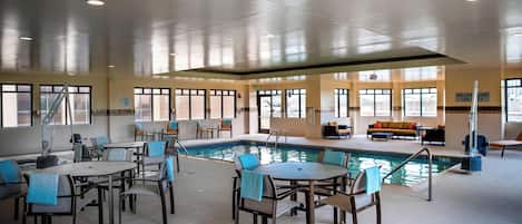 Un área de piscina interior con varias opciones de asientos y una mesa de billar.