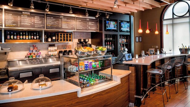 Un espace bar moderne doté d’un tableau affichant le menu, de tabourets et d’une variété de boissons.