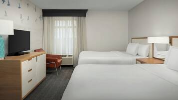 A hotel room with two beds, a desk, a TV, and a window with curtains.