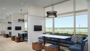 Un espace extérieur moderne aménagé avec un canapé, une table et des poufs, offrant une vue sur l’océan.