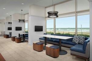 Uma área de estar moderna ao ar livre com sofá, mesa e pufes, com vista para o mar.