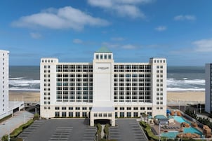 Hotel Courtyard com entrada central, estacionamento e área de piscina com formações rochosas.