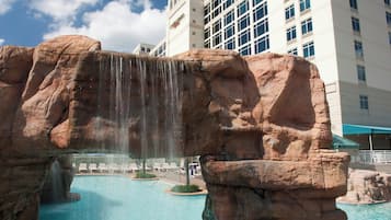 A hotel with a pool featuring a waterfall and rock formations.
