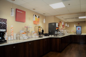 Zona de buffet con una estación de café, un refrigerador y diversos alimentos exhibidos en la barra.