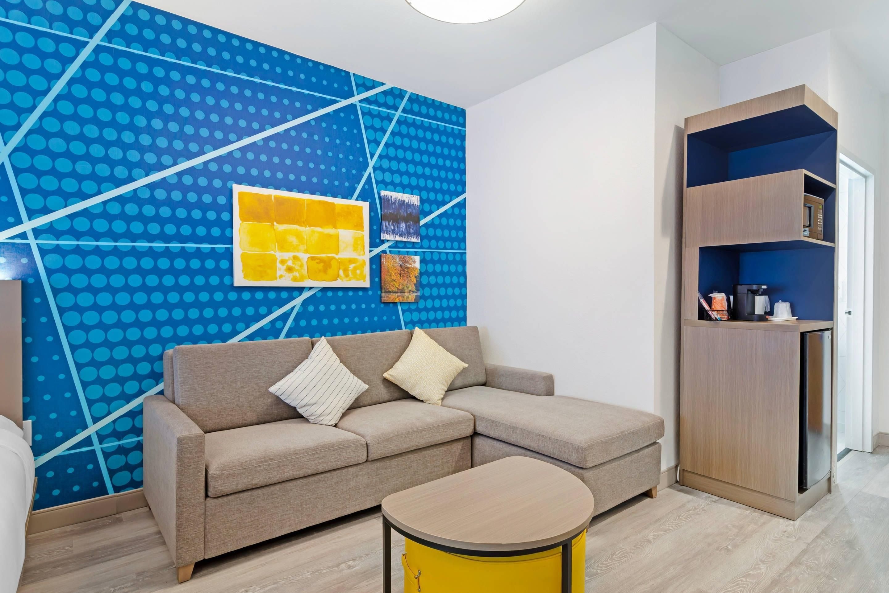 Una sala moderna con un sofá, una mesa de centro y una pared con un estampado de lunares azules.