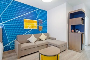 A modern living room with a sofa, a coffee table, and a wall with a blue polka dot pattern. - Comfort Suites Northside Hospital Gwinnett (Lawrenceville)