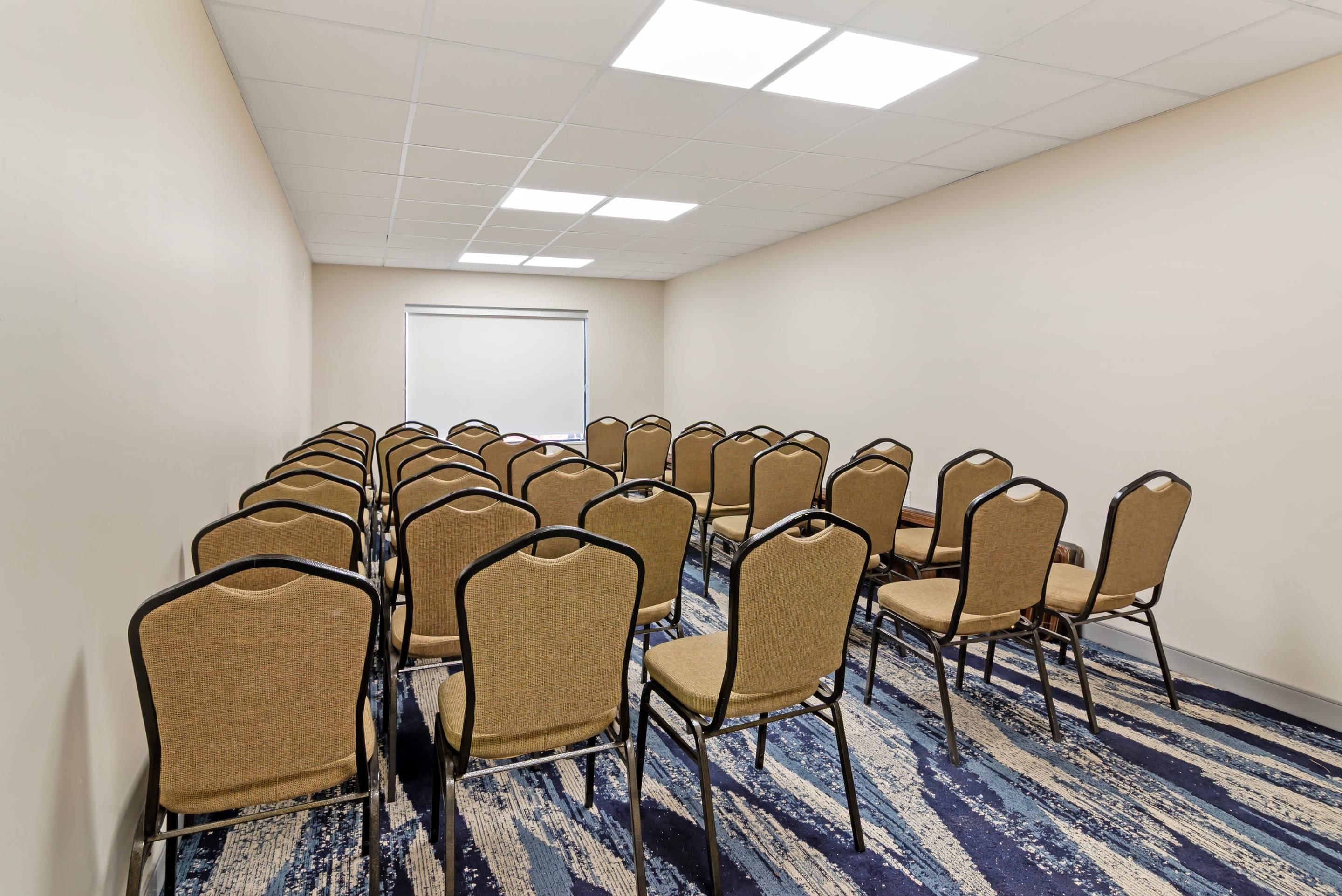 A conference room with rows of chairs, a whiteboard, and a carpeted floor.