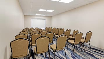 A conference room with rows of chairs, a whiteboard, and a carpeted floor.