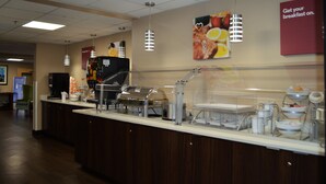 Una barra de desayuno con diversas estaciones de comida y una máquina de café.