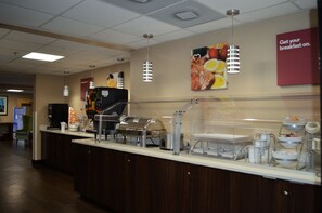 Una barra de desayuno con diversas estaciones de comida y una máquina de café.