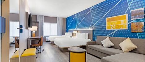 A hotel room with a bed, a sofa, a desk, a chair, and a lamp.