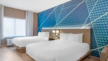 Een hotelkamer met twee bedden, een groot raam en een modern wandontwerp.