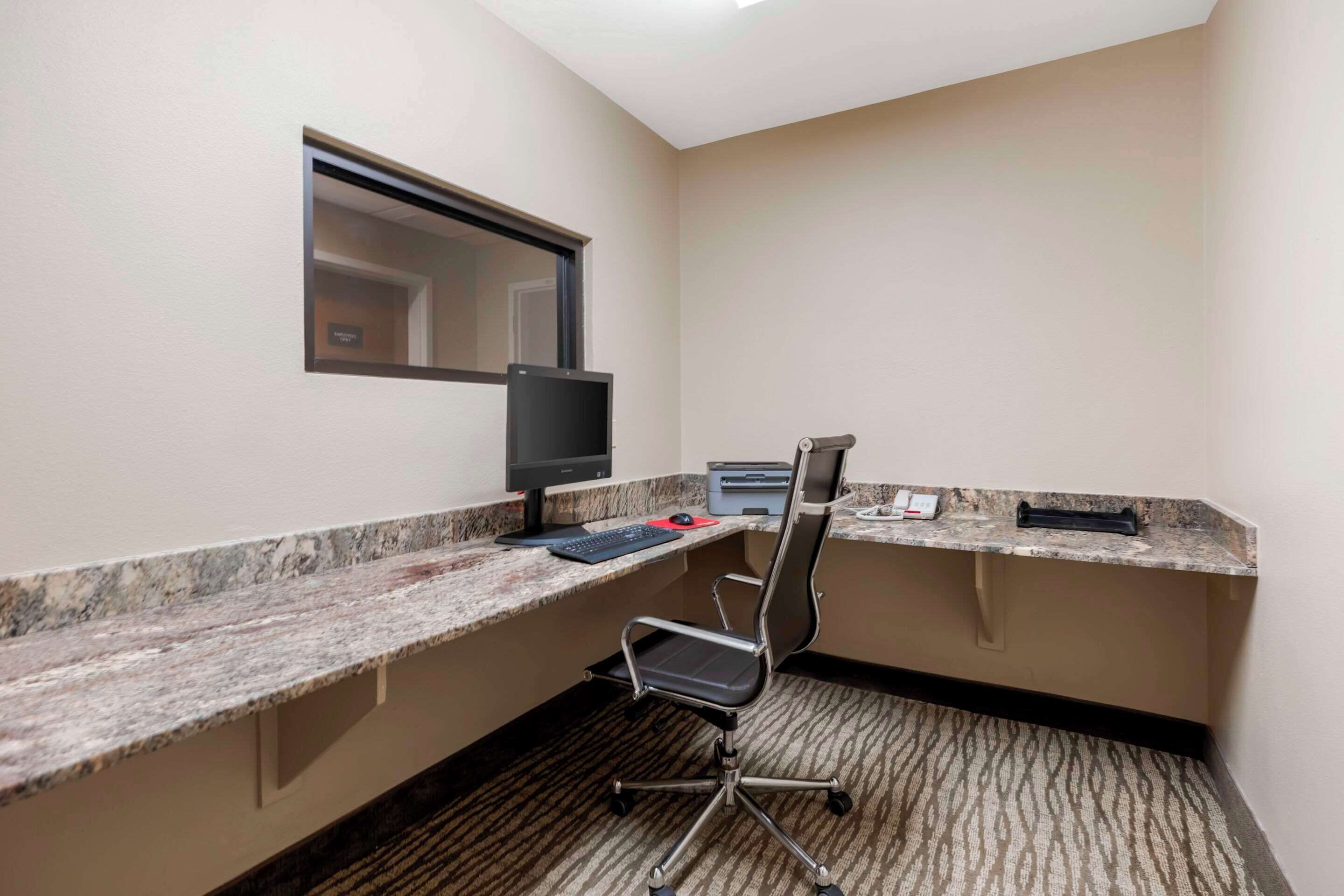 A small office space with a desk, chair, computer, printer, and telephone.