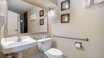 A bathroom with a white sink, toilet, and mirror. There are three framed pictures on the wall and a towel rack with towels.