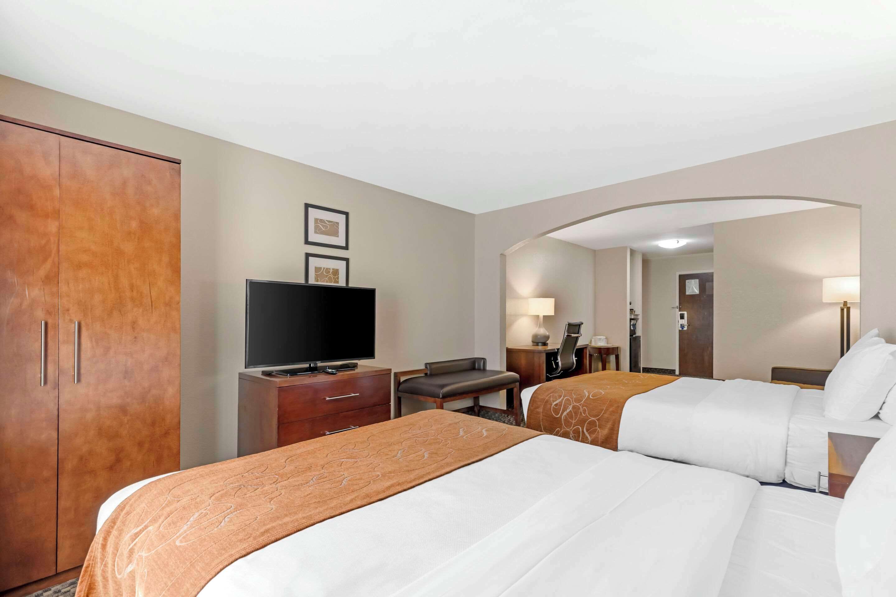 Une chambre d’hôtel avec deux lits, une télévision, un bureau et une armoire.