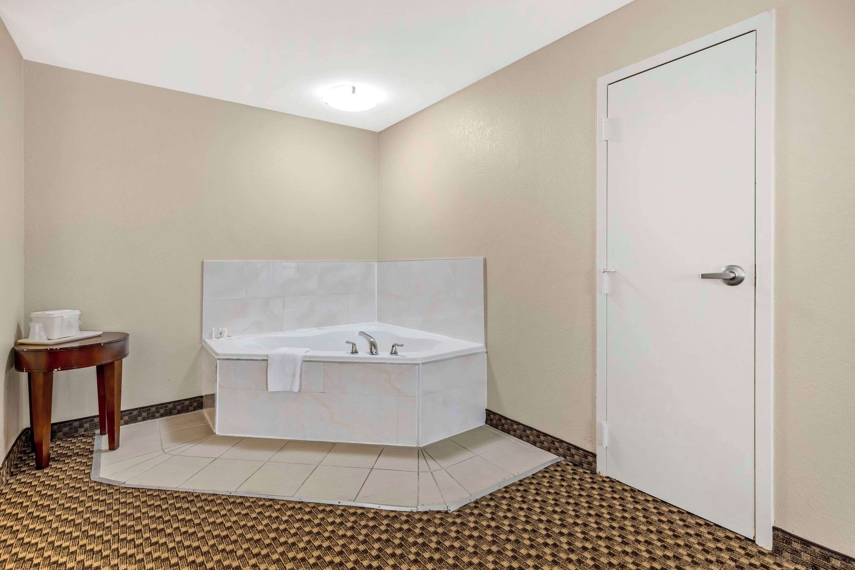 Ein Badezimmer mit einer weißen Badewanne, einem kleinen runden Tisch mit Tassen und einer Tür.