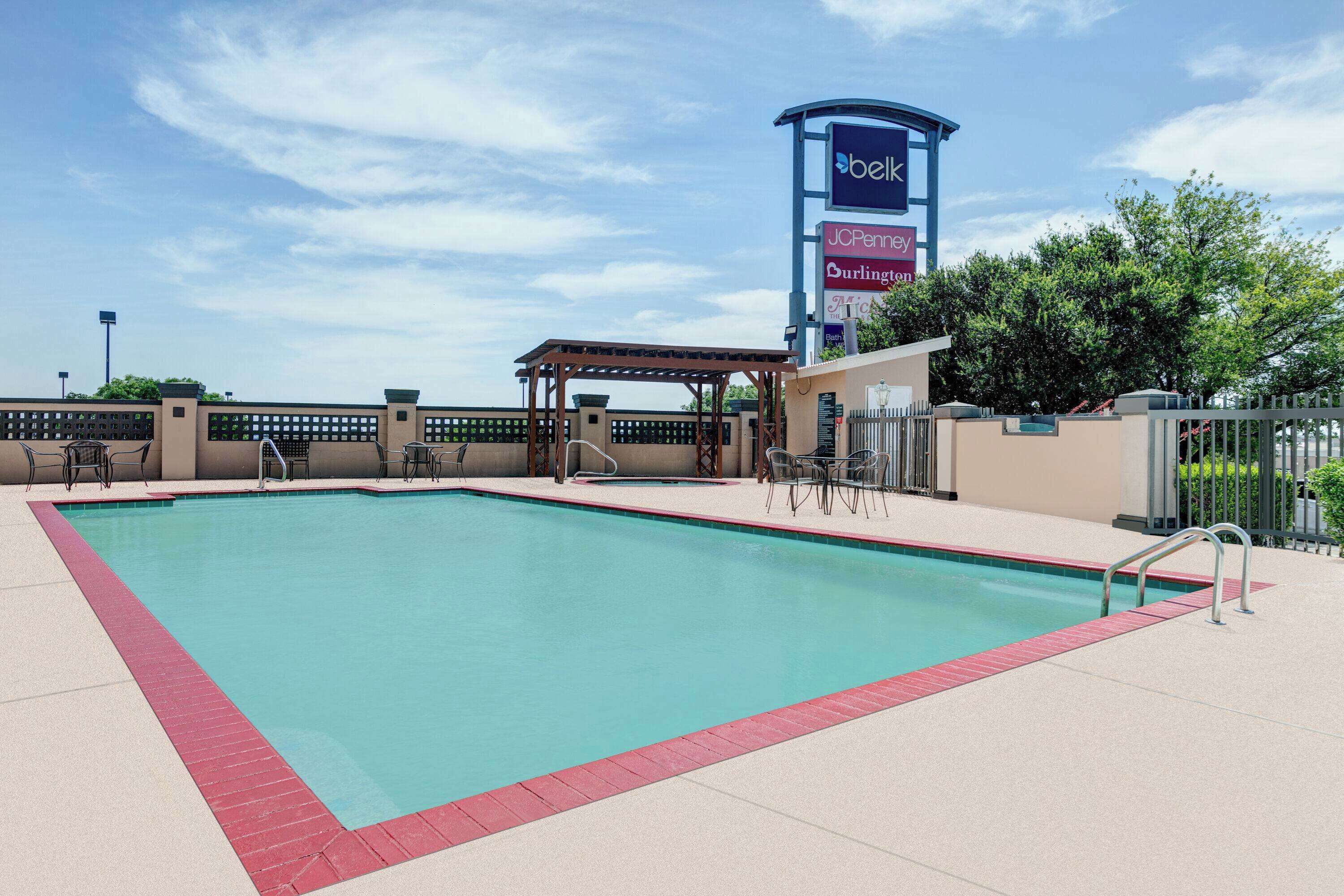 A swimming pool with a red border, a covered seating area, and a sign for JC Penney and Burlington.