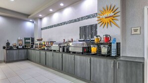 A bright side breakfast buffet with various food stations and a sign indicating food prep area. - La Quinta Inn & Suites by Wyndham Weatherford (Weatherford)