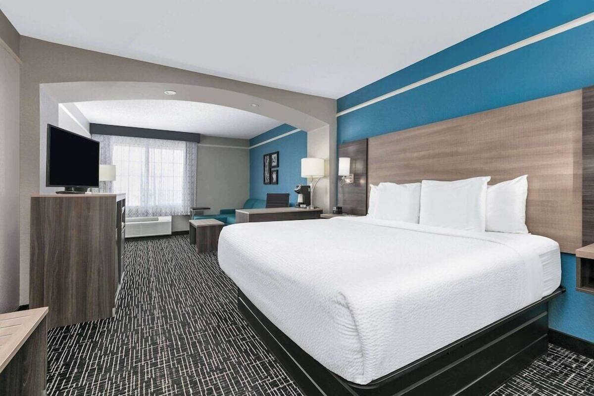 A hotel room with a large bed, a desk, a television, and a bathroom.