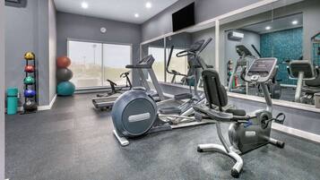 Un gimnasio con cintas de correr, elípticas y diferentes pelotas de ejercicio.