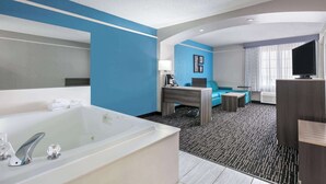 A modern hotel room with a large bathtub, a sofa, a desk, and a television. - La Quinta Inn & Suites by Wyndham Weatherford (Weatherford)