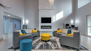 A modern lobby with a fireplace, sofas, and a large rug. - La Quinta Inn & Suites by Wyndham Weatherford (Weatherford)