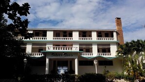 A two-story hotel with a balcony on the ground floor and a brick chimney on the right.