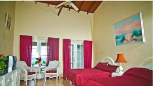 A hotel room with two beds, a dining area with a table and chairs, and a ceiling fan.
