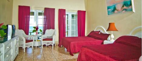 A hotel room with two beds, a dining area with a table and chairs, and a ceiling fan.