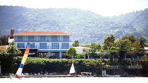A coastal building with a red roof, multiple windows, and a balcony.