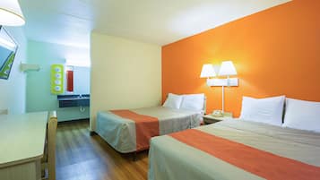 Una habitación de hotel con dos camas, un escritorio, un espejo y una ventana.