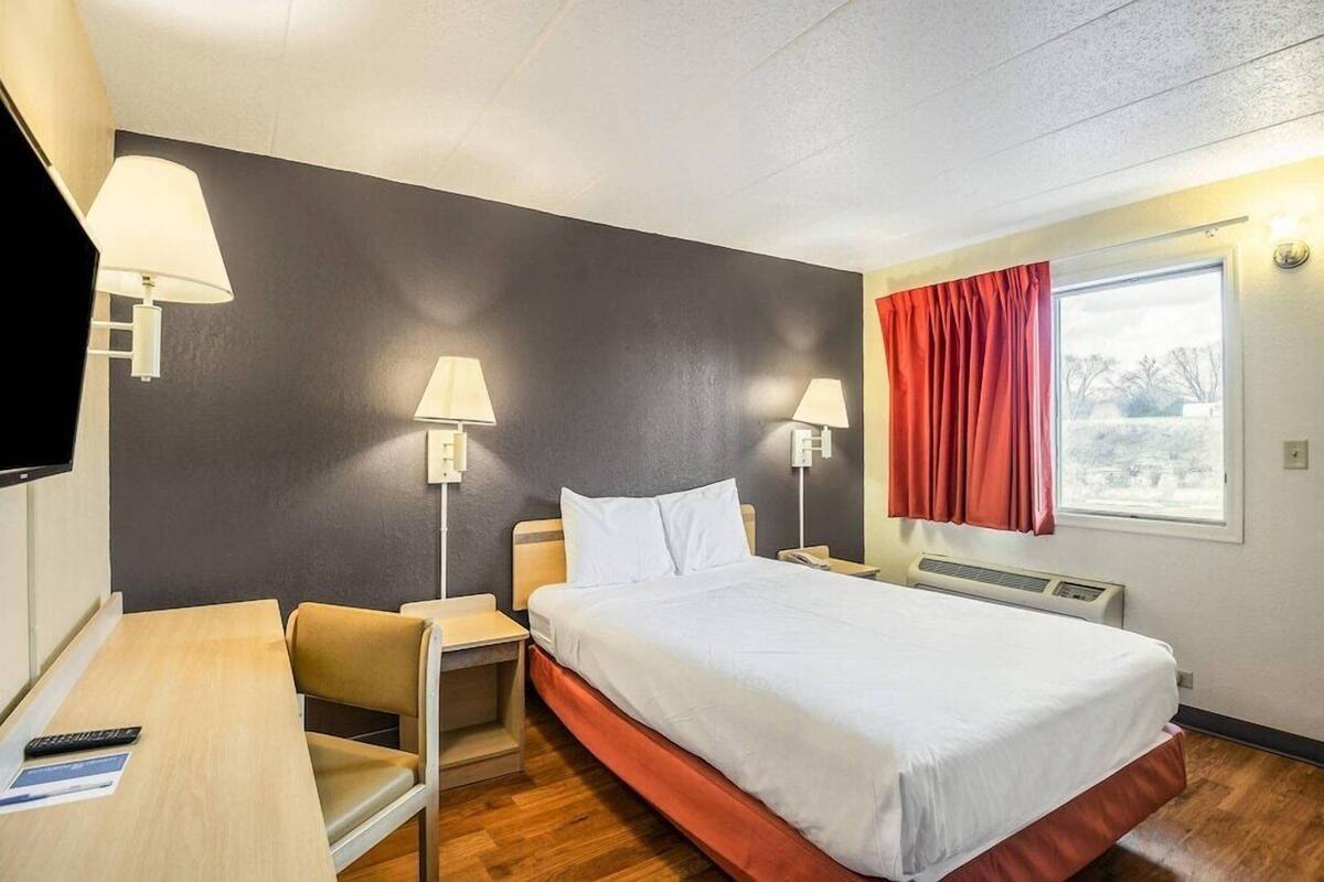 A hotel room with a bed, bedside tables, a desk, and a chair.