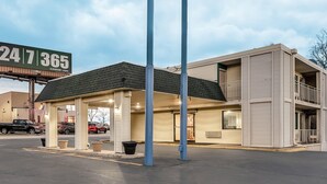 Un motel doté d’un parking couvert, d’un panneau indiquant une station-service et d’un bâtiment à deux étages avec des balcons.